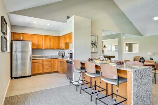 A kitchen with wooden cabinets and a stainless steel refrigerator.