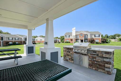 A patio with a grill and picnic table.