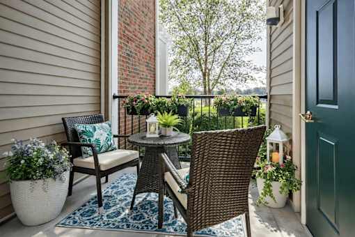 A patio with a wicker chair and table.