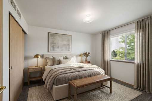 A bedroom with a large bed, a nightstand, a lamp, and a window with curtains.