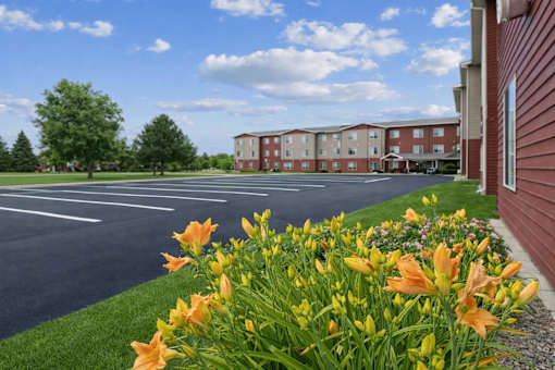 A parking lot with a building in the background and orange flowers in the foreground.