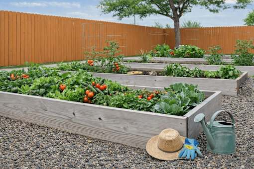 A garden with a wooden box, a straw hat, a blue glove, and a green watering can.