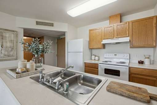 A kitchen with a white counter top and wooden cabinets.