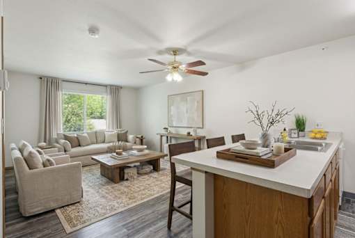 A well-lit, spacious living room with a kitchen area in the background.