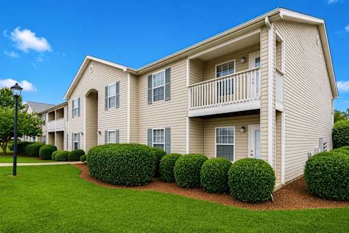 A beige two-story apartment building with a balcony on the second floor.