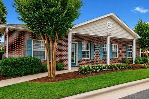 A small brick house with a tree in front.