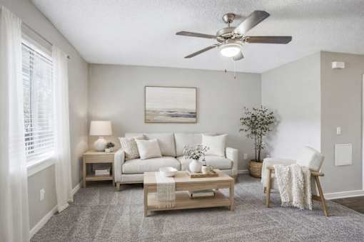Cozy living room with neutral tones and ceiling fan at Davidson Homes Apartments, North Carolina