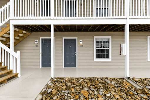 A house with a grey siding and a white porch.