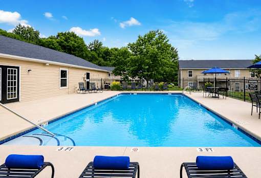 A swimming pool with blue water and lounge chairs.