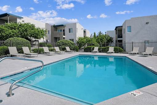 Community pool with lounge chairs and landscaping at Vista Linda Apartments, New Mexico, 87507