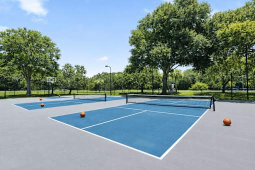 A blue tennis court with orange balls and a net. at Epic Apartments , Florida, 32114