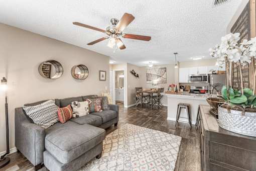 A living room with a grey couch and a ceiling fan. at Epic Apartments , Apartments, Daytona Beach, FL