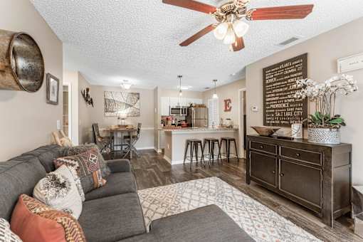 A living room with a grey couch and a wooden cabinet. at Epic Apartments , Florida