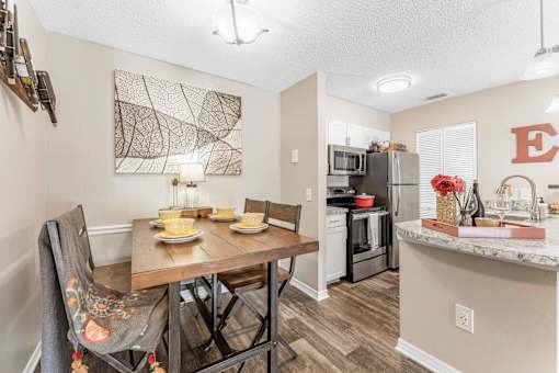 A kitchen with a table set for two and a painting on the wall. at Epic Apartments , Apartments, Daytona Beach, FL