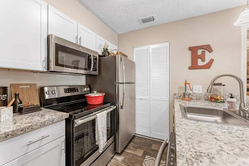 A kitchen with a black stove top oven and a black microwave above it at Epic Apartments , Daytona Beach, Florida