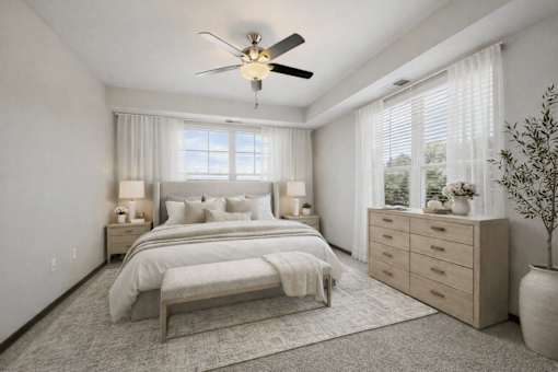 A bedroom with a large bed, a ceiling fan, and a window with blinds.