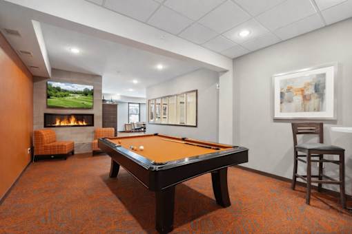 A room with a pool table and a fireplace.