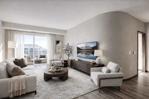 A modern living room with a large couch, a coffee table, and a TV mounted on the wall.