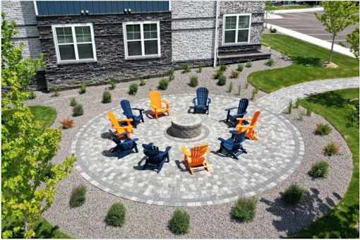 A stone building with a circular patio and chairs around a fire pit.