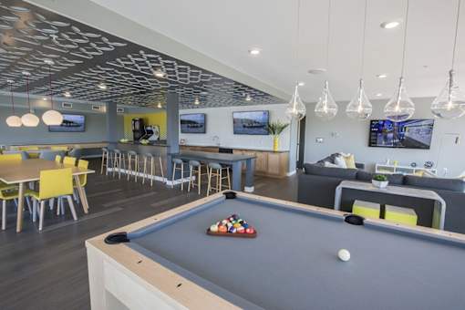 Community clubhouse with pool table and lounge seating at Hello Apartments, Minnesota