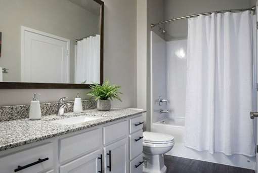 Modern bathroom with granite countertop and white cabinetry at Hello Apartments, Minneapolis, MN