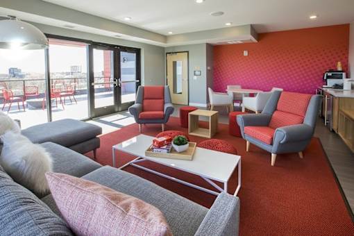 Resident lounge with colorful accent wall and outdoor terrace at Hello Apartments, Minnesota, 55427