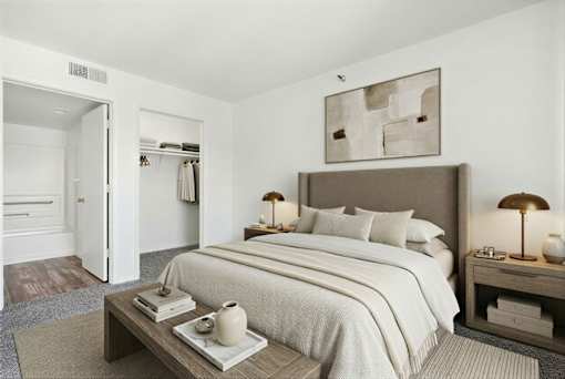 A bedroom with a large bed and a nightstand with a lamp.