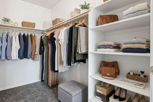 A well-organized closet with clothes and shoes neatly arranged on shelves and hangers.