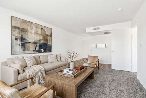 A living room with a large painting on the wall and a coffee table in the center.