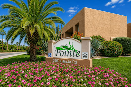 A sign for Pointe at 3200 Baristo Rd is in front of a building and a palm tree.