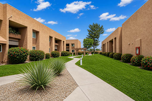 A long concrete walkway leads between two rows of tan buildings.