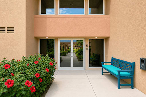A blue bench sits in front of a building with a glass door.