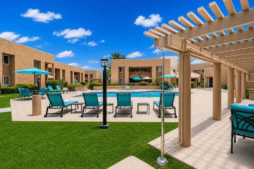 A pool surrounded by chairs and umbrellas with a building in the background.