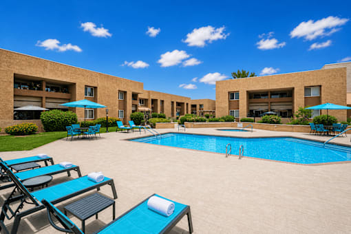 A pool area with sun loungers and umbrellas.