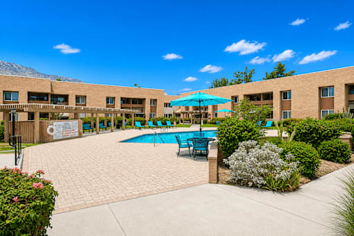 A pool area with a blue umbrella and chairs.