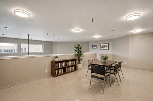 A room with a table, chairs, and a bookshelf.