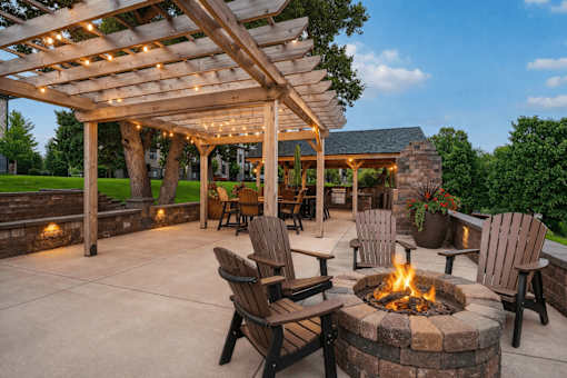 A patio with a fire pit and chairs under a pergola at Aster Meadow, Vadnais Heights, MN, 55127
