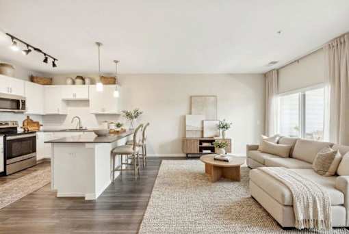A modern kitchen with white appliances and a dining area with a white couch at Aster Meadow, Vadnais Heights, MN, 55127