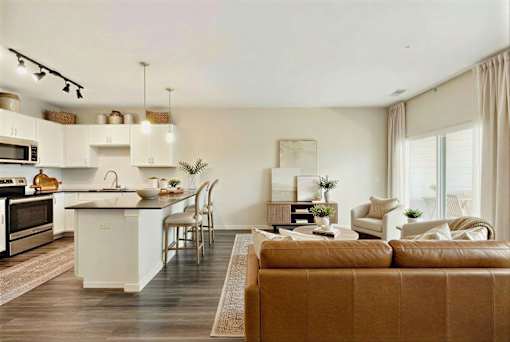 A modern kitchen with a brown sofa in front of it at Aster Meadow, Vadnais Heights, MN, 55127