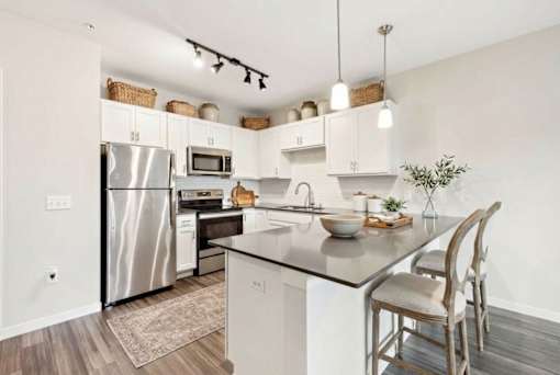 A modern kitchen with a stainless steel refrigerator and wooden flooring at Aster Meadow, Vadnais Heights, MN, 55127
