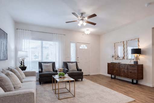 A living room with a grey couch, two chairs, a coffee table, and a wooden cabinet.
