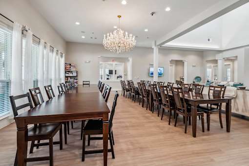 A long wooden table is surrounded by chairs in a room with a chandelier.