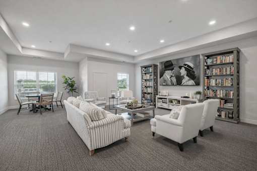 Community lounge with striped sofas and bookcase entertainment center at The Hendrickson Apartments, Falcon Heights, 55113
