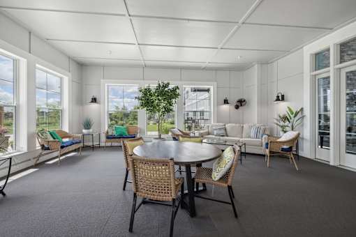 Screened porch with dining table and wicker furniture at The Hendrickson Apartments, Falcon Heights, MN