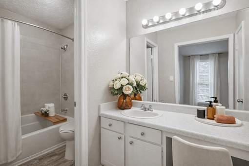 A white bathroom with a vanity, toilet, and a shower.