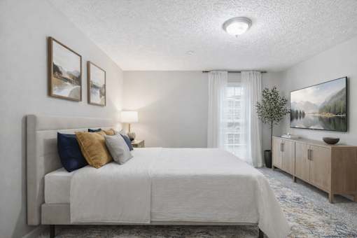 A bedroom with a large bed, a nightstand with a lamp, and a painting on the wall.