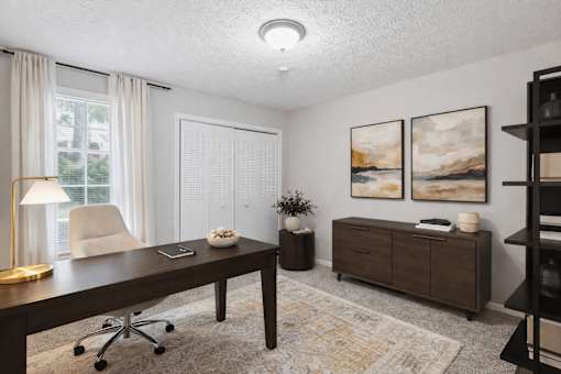 A room with a desk, chair, and two paintings on the wall.