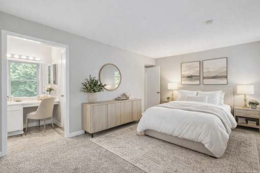 A bedroom with a large bed, a desk with a chair, and a window.