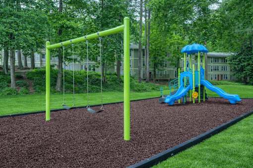 A playground with a blue slide and a green swing set.