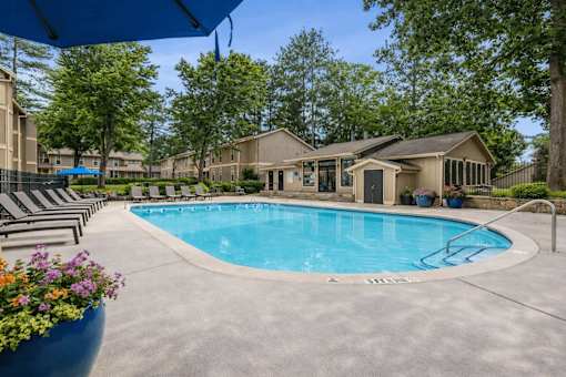 A swimming pool surrounded by lounge chairs and trees.